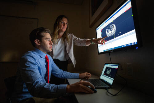 two students observe a brain scan on a screen